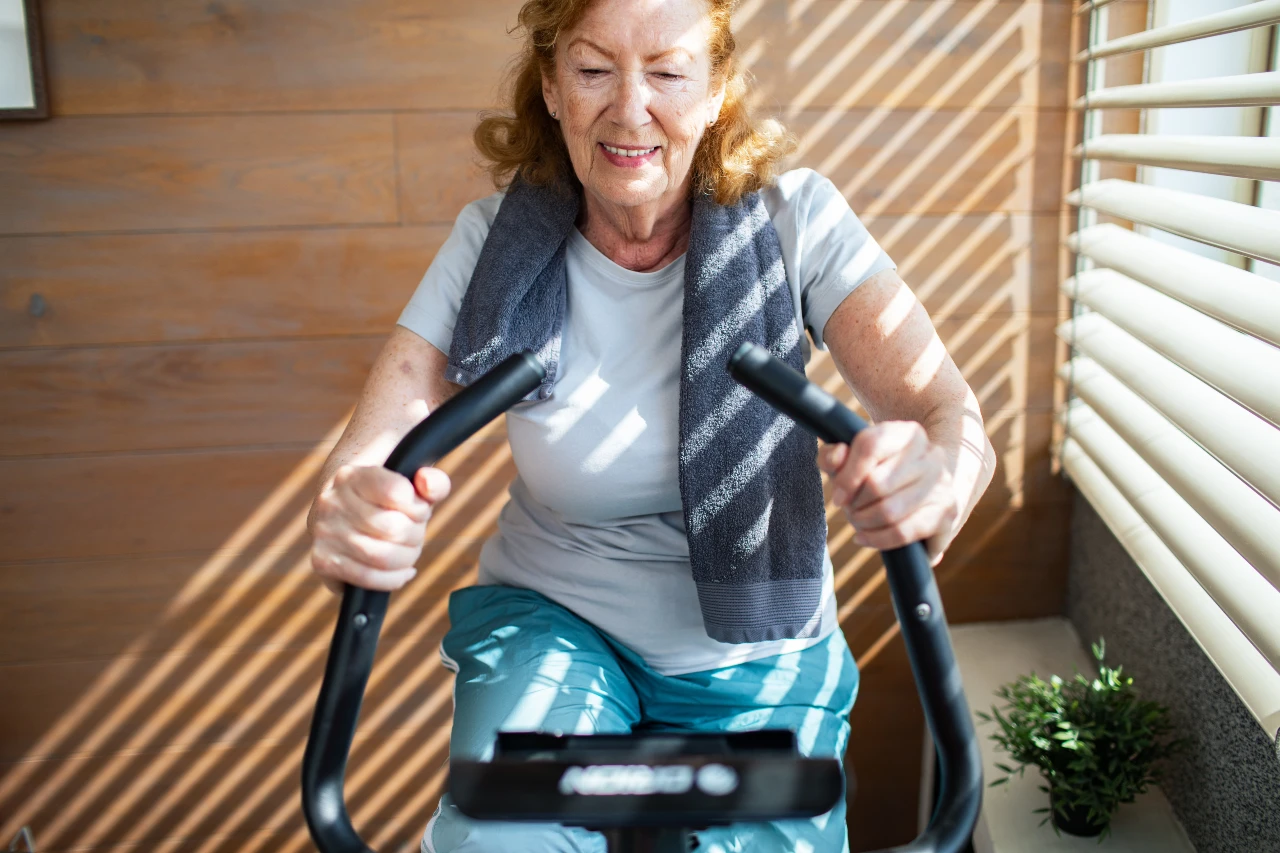 Seniorin trainiert zuhause auf Pedaltrainer