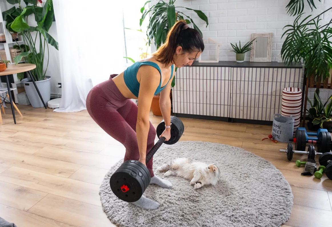 Woman training with a barbell at home in the living room