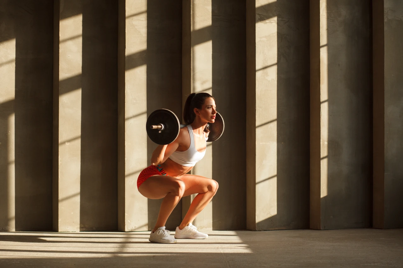Woman performing barbell squats to help prevent osteoporosis